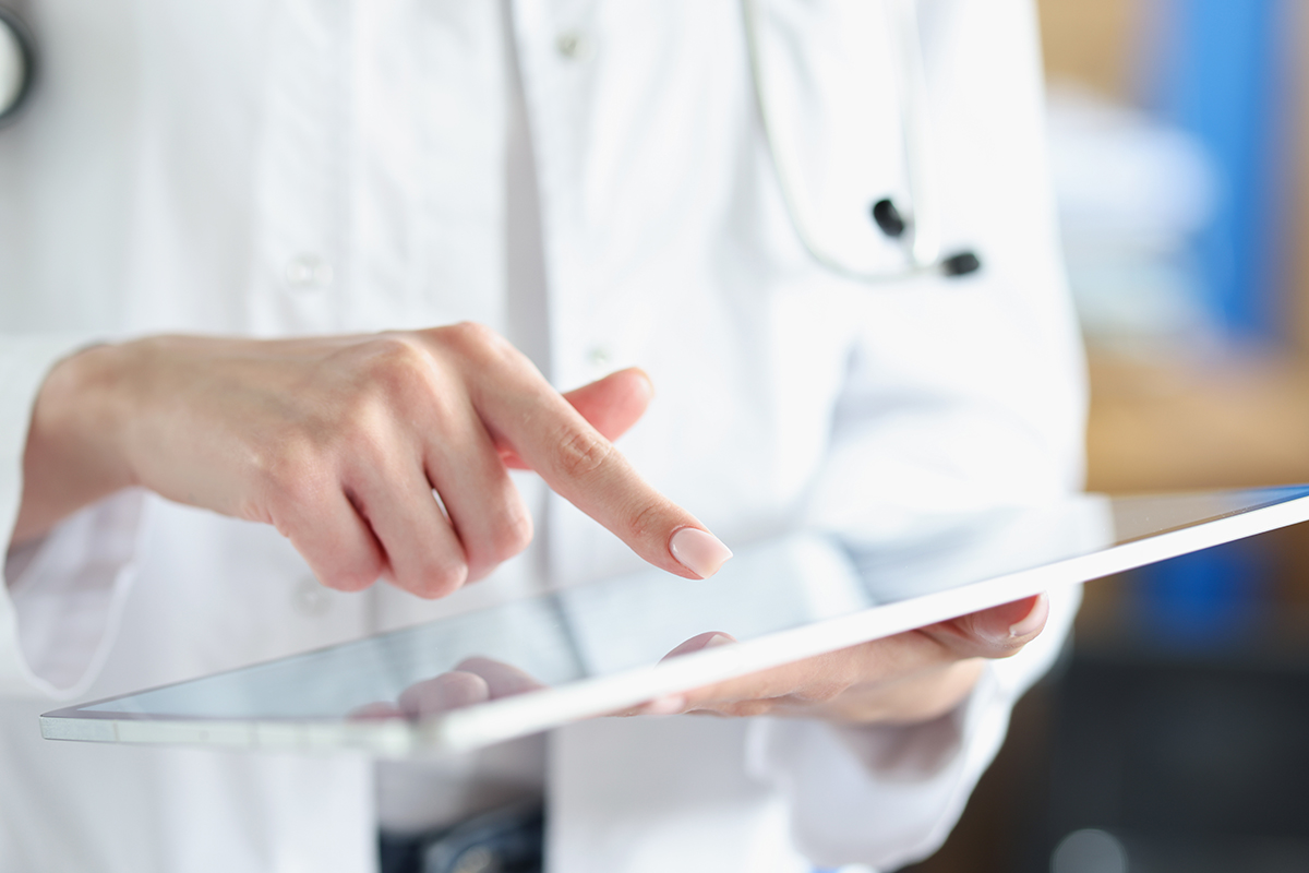 Doktor im weißen Kittel interagiert mit einem Tablet