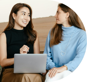 two women sitting together with laptop