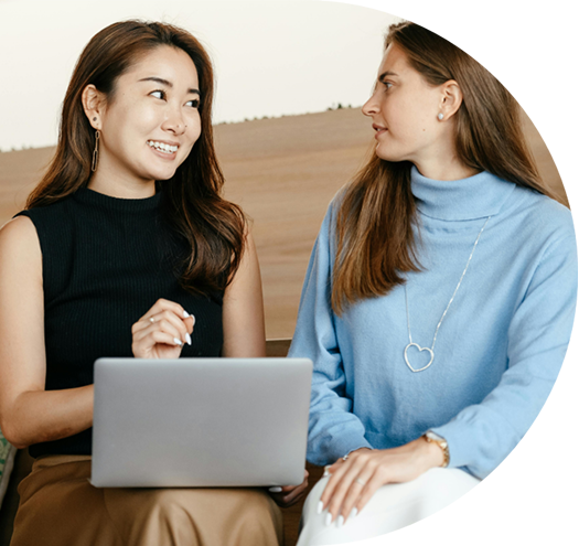 two women sitting together with laptop